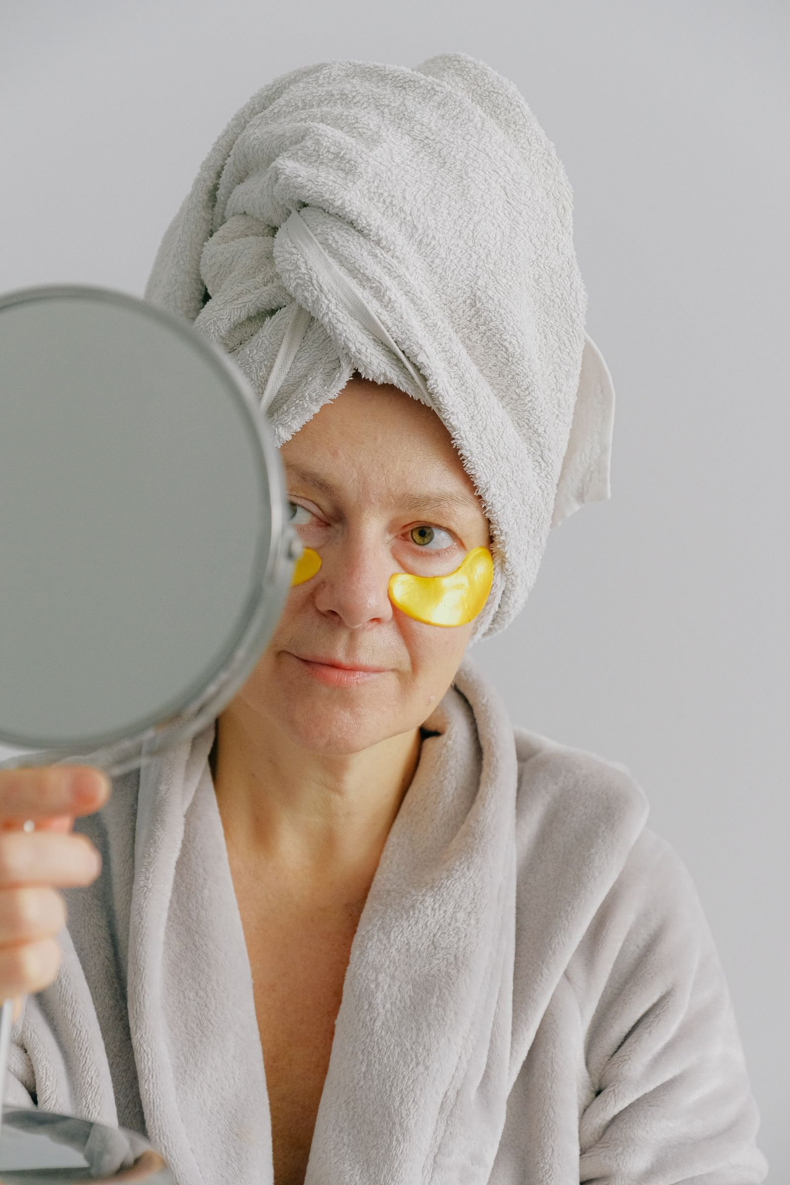 Middle-aged woman checking her skin in a mirror during a calm skincare routine